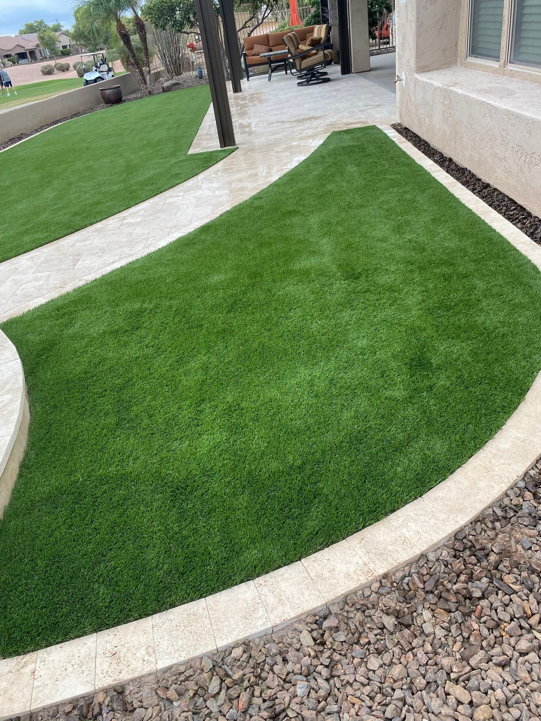 A lush green lawn with a walkway surrounded by gravel.