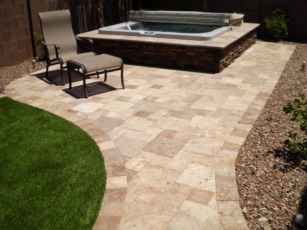 A patio with a chair and a hot tub in the backyard.