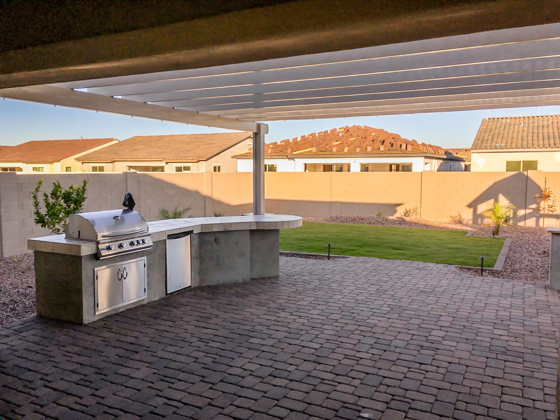A patio with a grill and a pergola over it