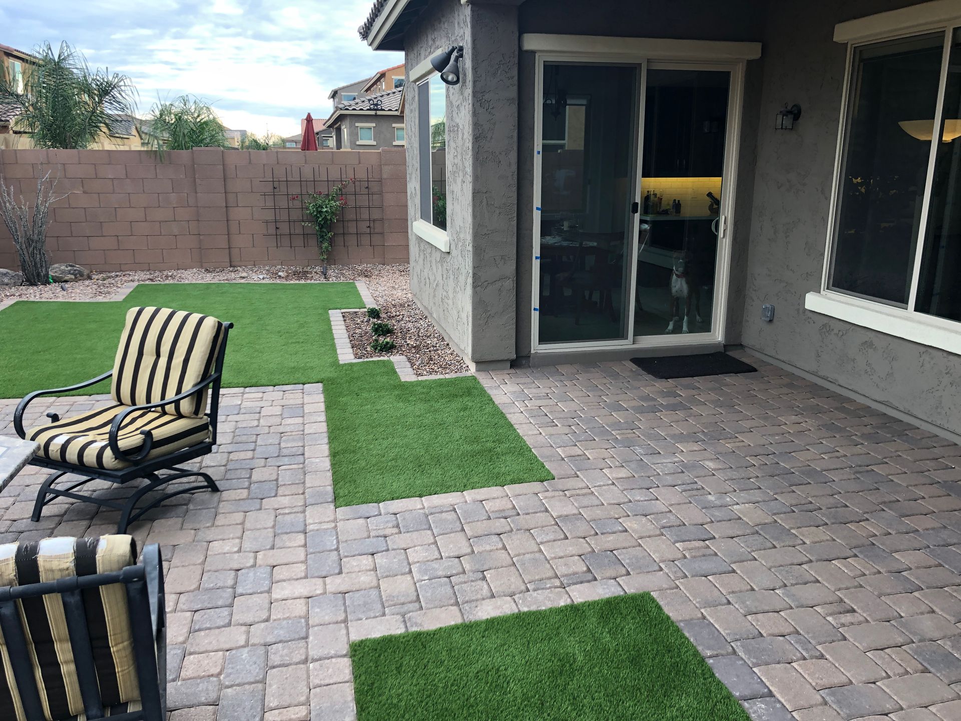 A patio with chairs and a sliding glass door in the backyard of a house.