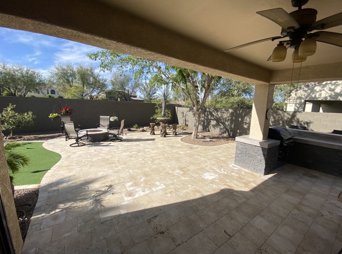 A patio with a table and chairs and a ceiling fan.