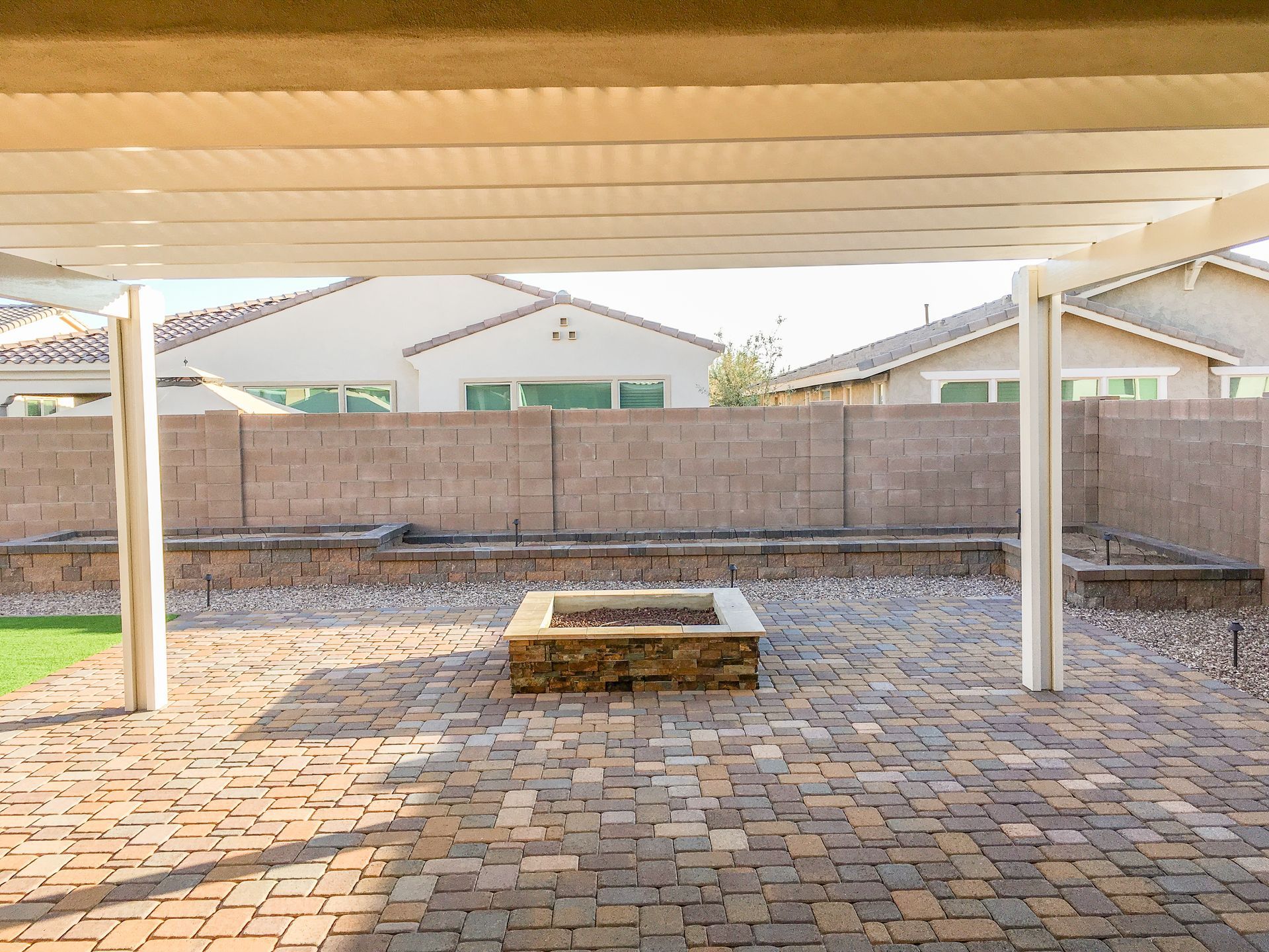 There is a fire pit in the backyard under a pergola.