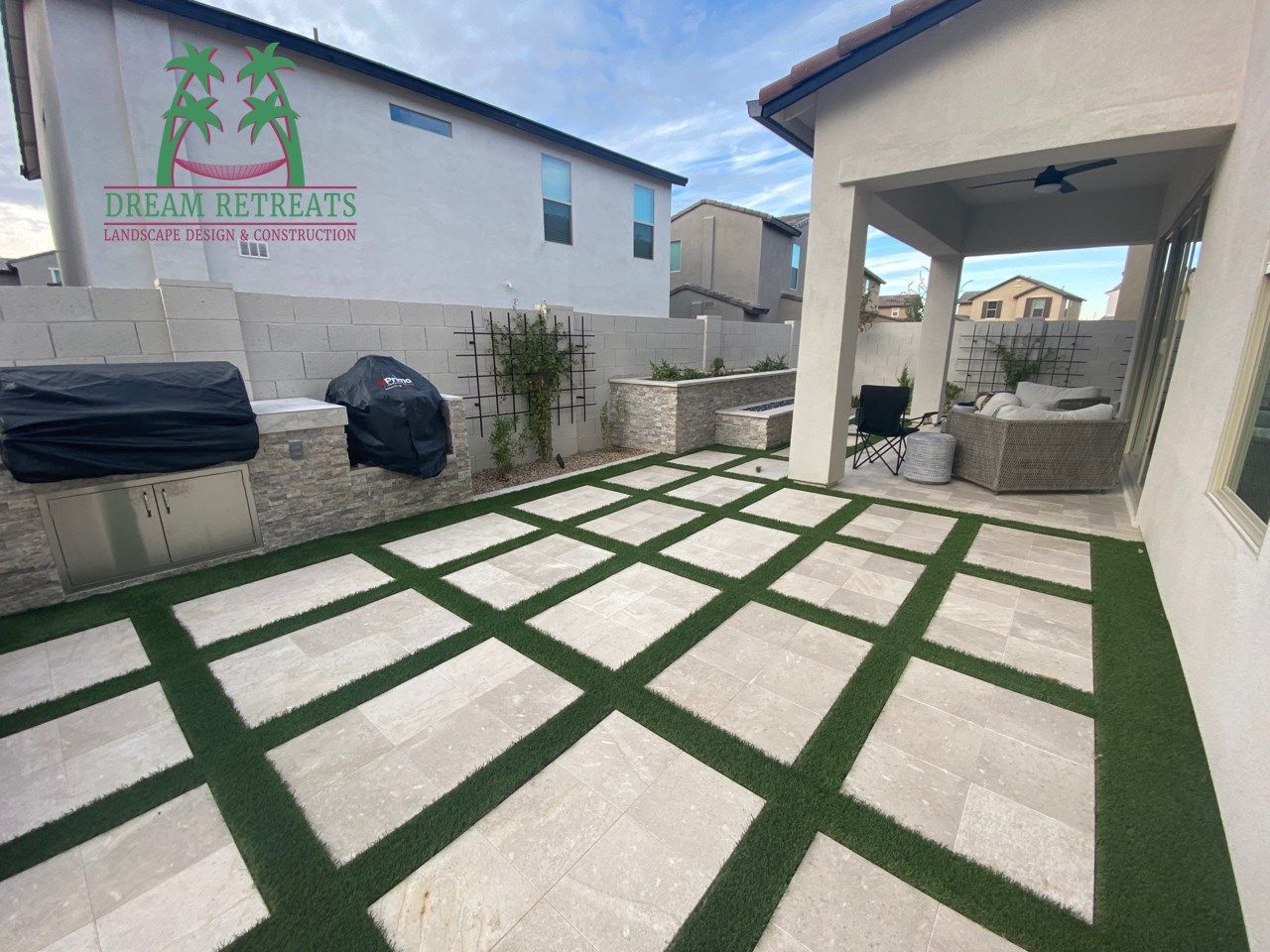 A patio with a grill and a lawn in front of a house.