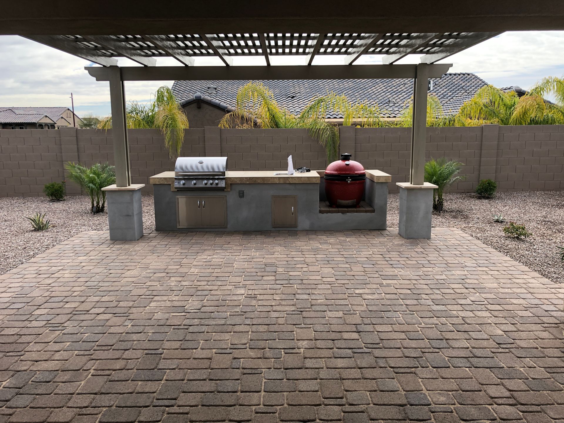 A brick patio with a grill under a pergola