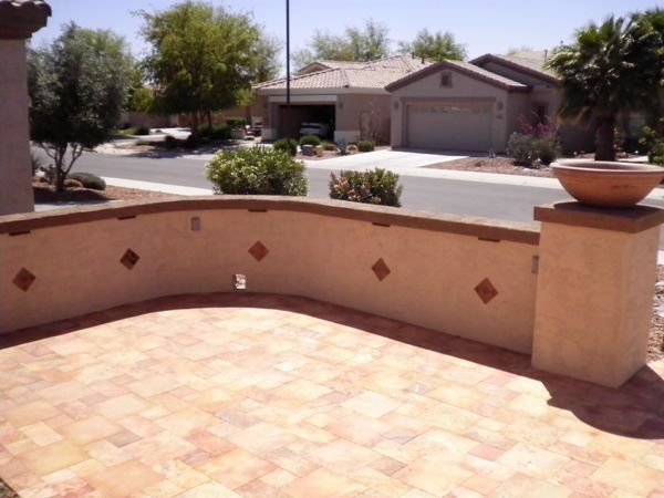 A house with a garage is behind a brick wall