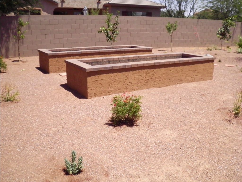 Two brick planters are sitting in the dirt in front of a brick wall