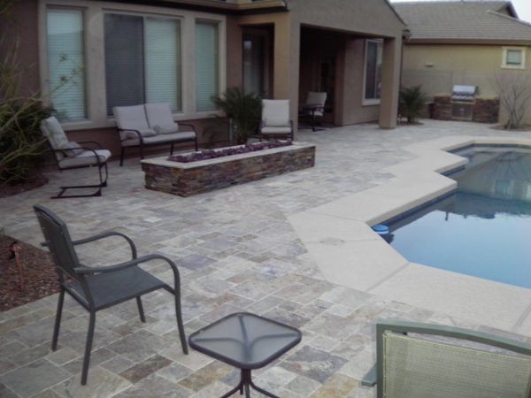 A patio with chairs and a table next to a pool
