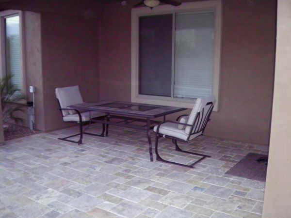 A patio with a table and chairs in front of a window