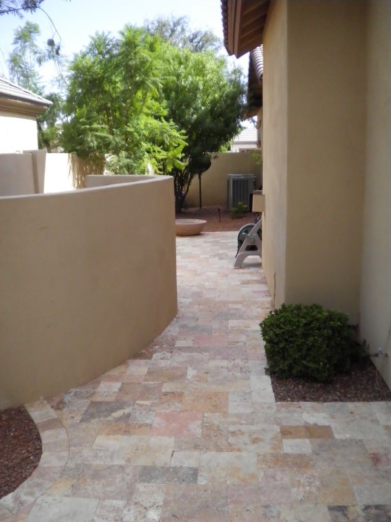 A stone walkway between two buildings with trees in the background