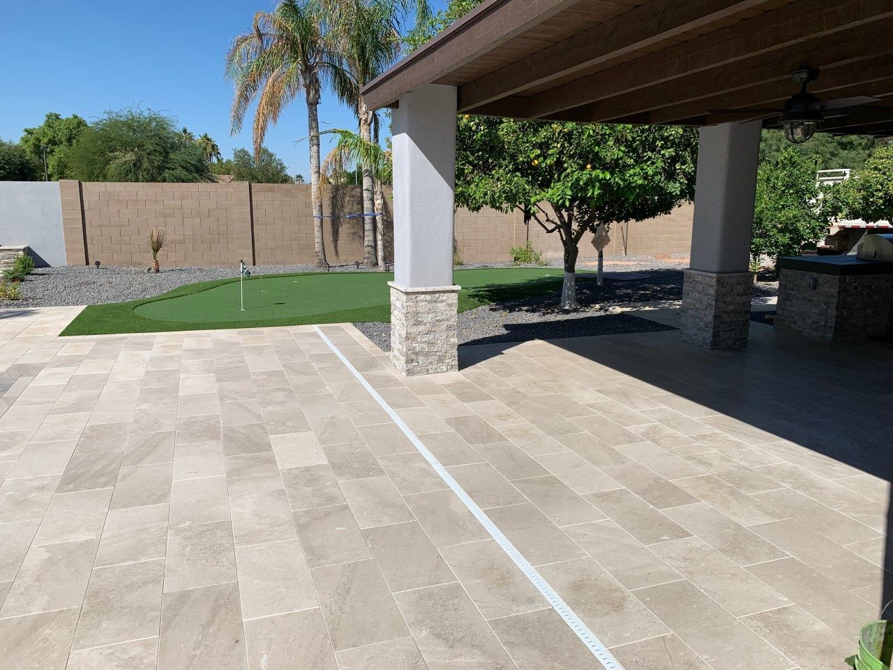 A patio with a ceiling fan and a few trees in the background