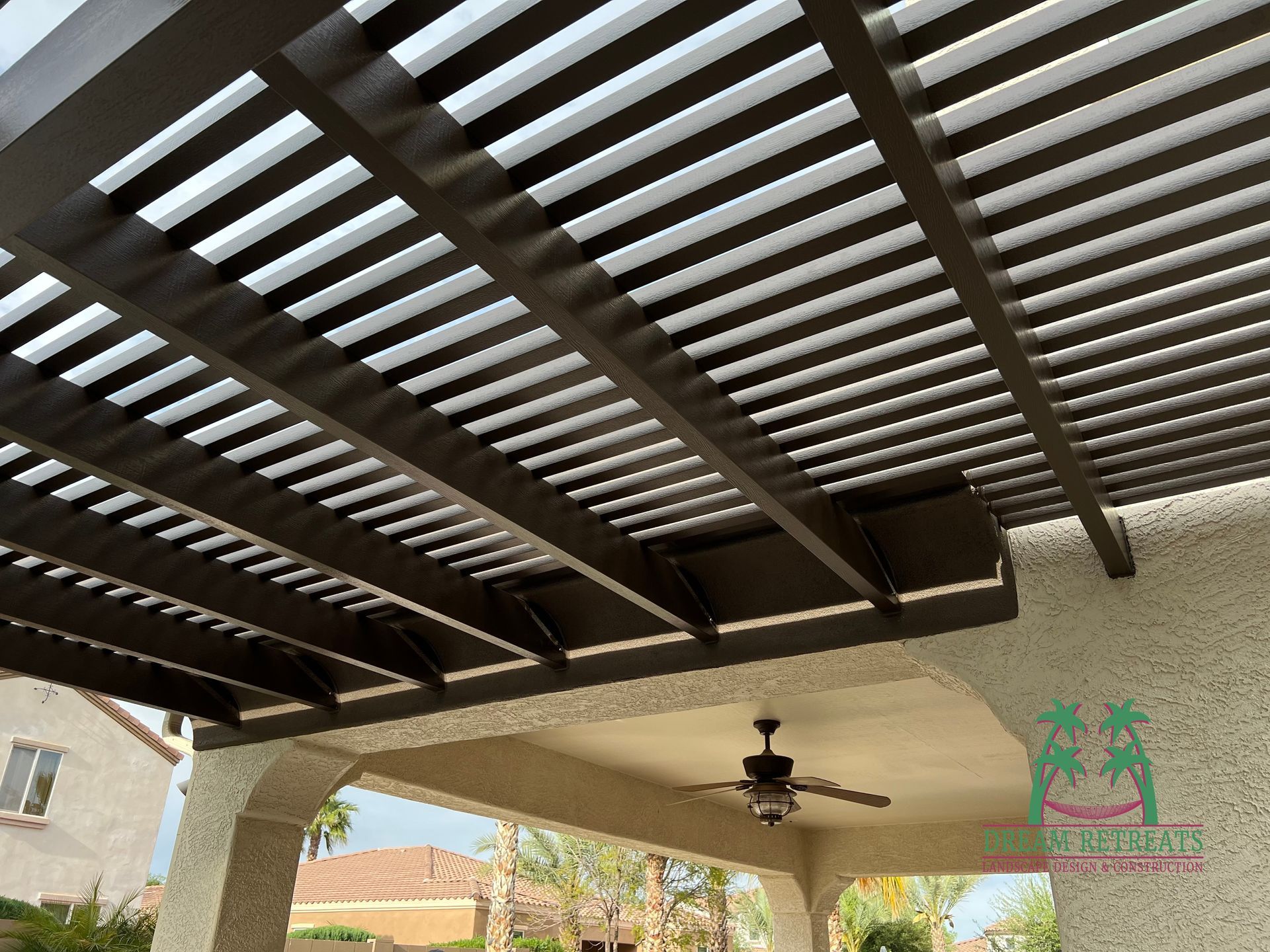A ceiling fan is hanging from the ceiling of a pergola.