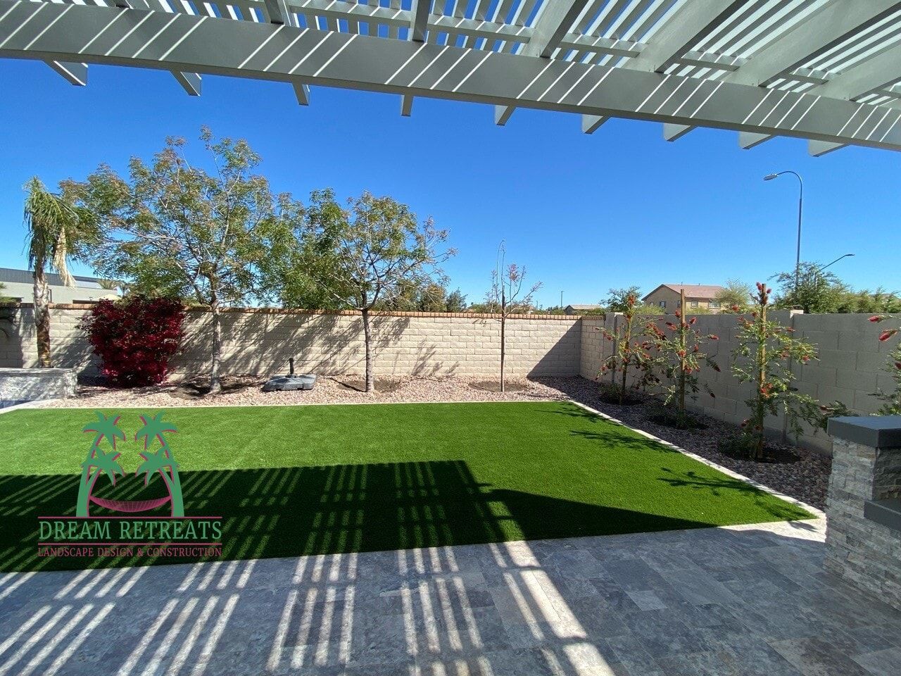 A backyard with a pergola and a lush green lawn