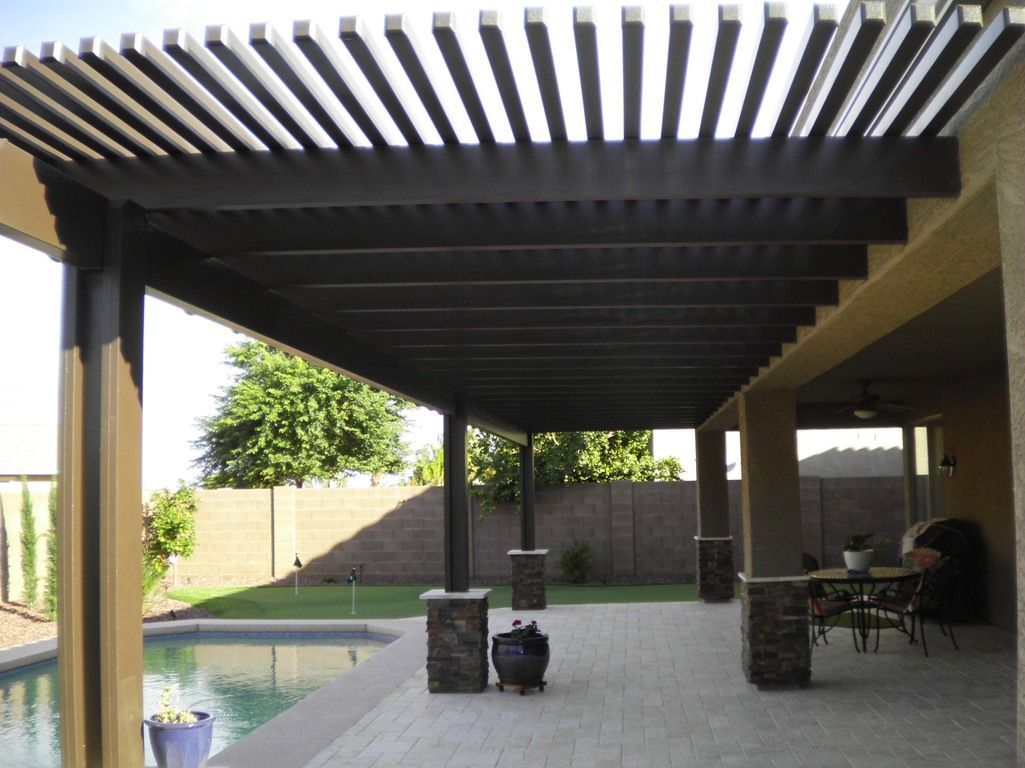 A pergola over a patio with a pool in the background