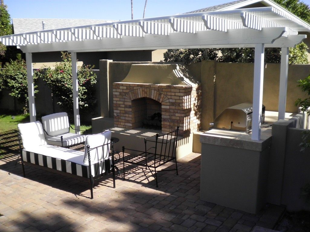 A patio with a fireplace and a white pergola