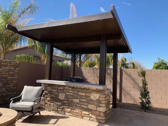 A patio with a stone bar , chairs , and a fire pit.