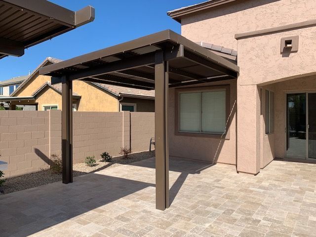 A patio with a pergola in front of a house