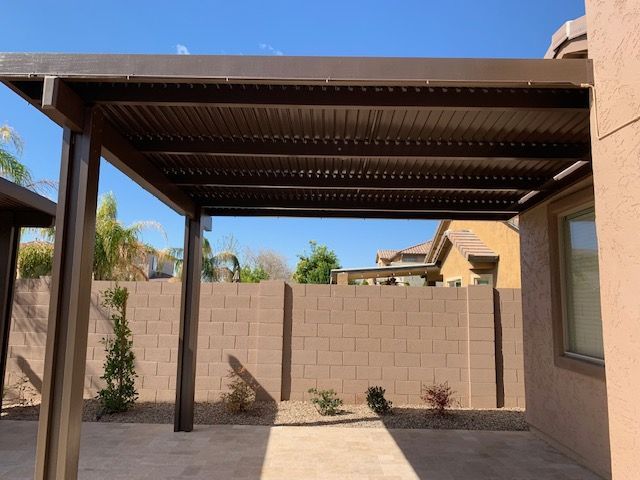 A patio with a canopy over it and a brick wall behind it.
