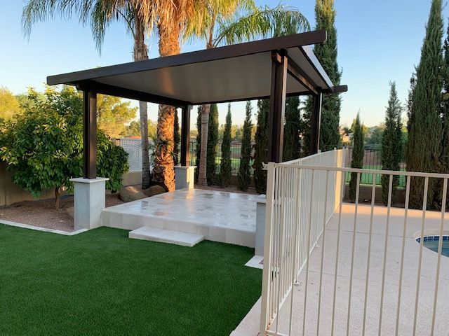 There is a gazebo in the backyard with a pool in the background.