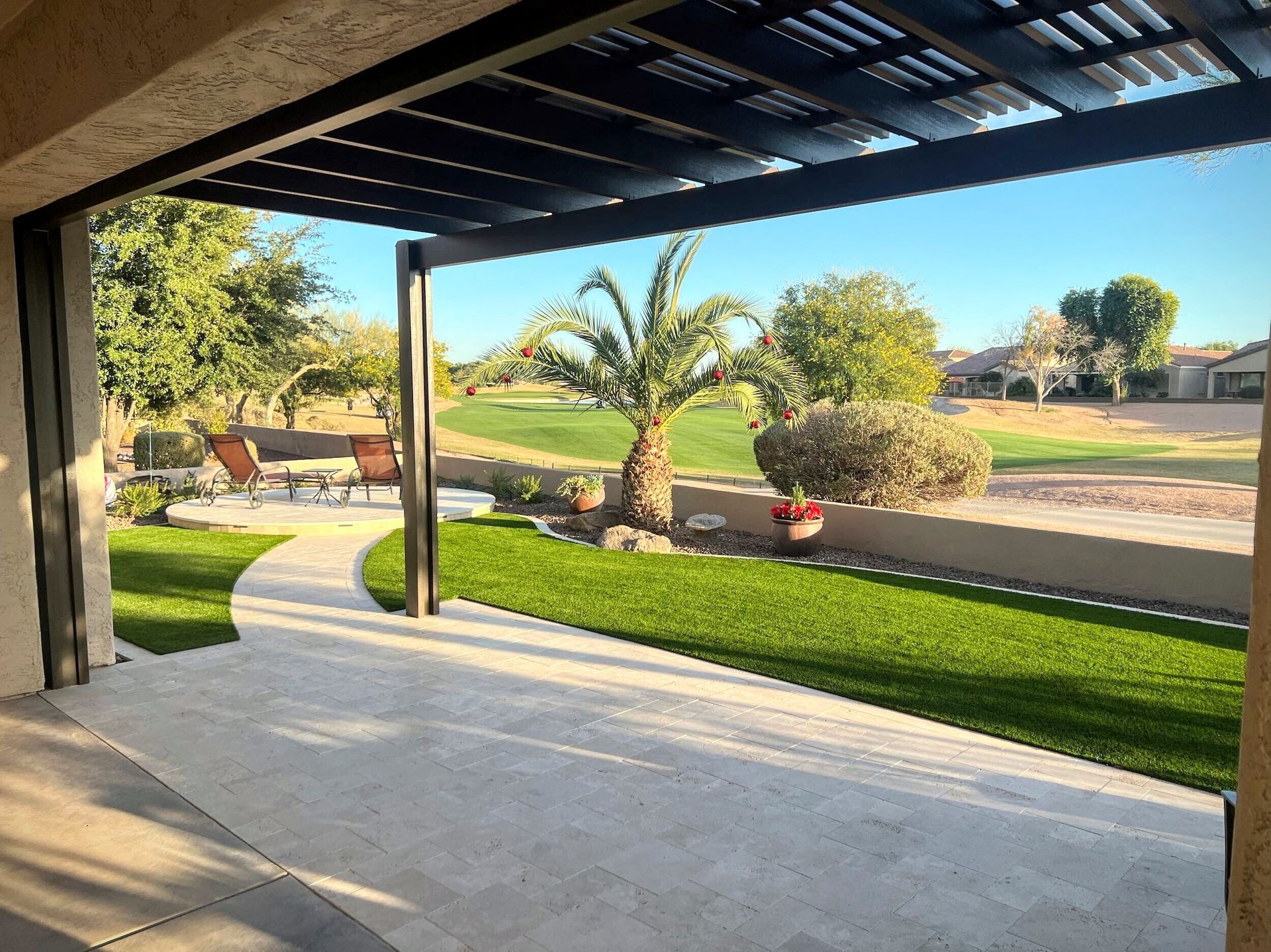 A patio with a pergola and a view of a golf course.