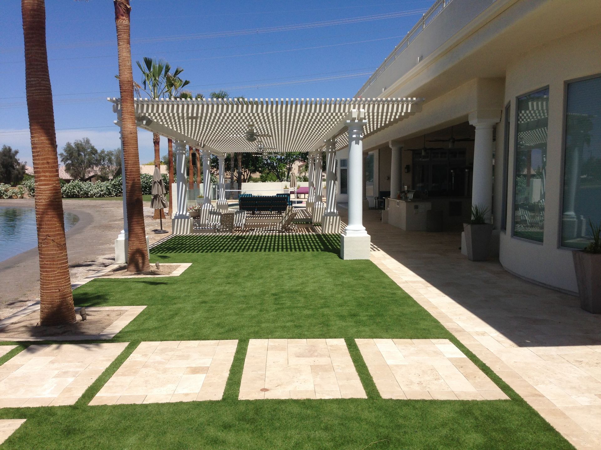 A house with a pergola and a lawn in front of it