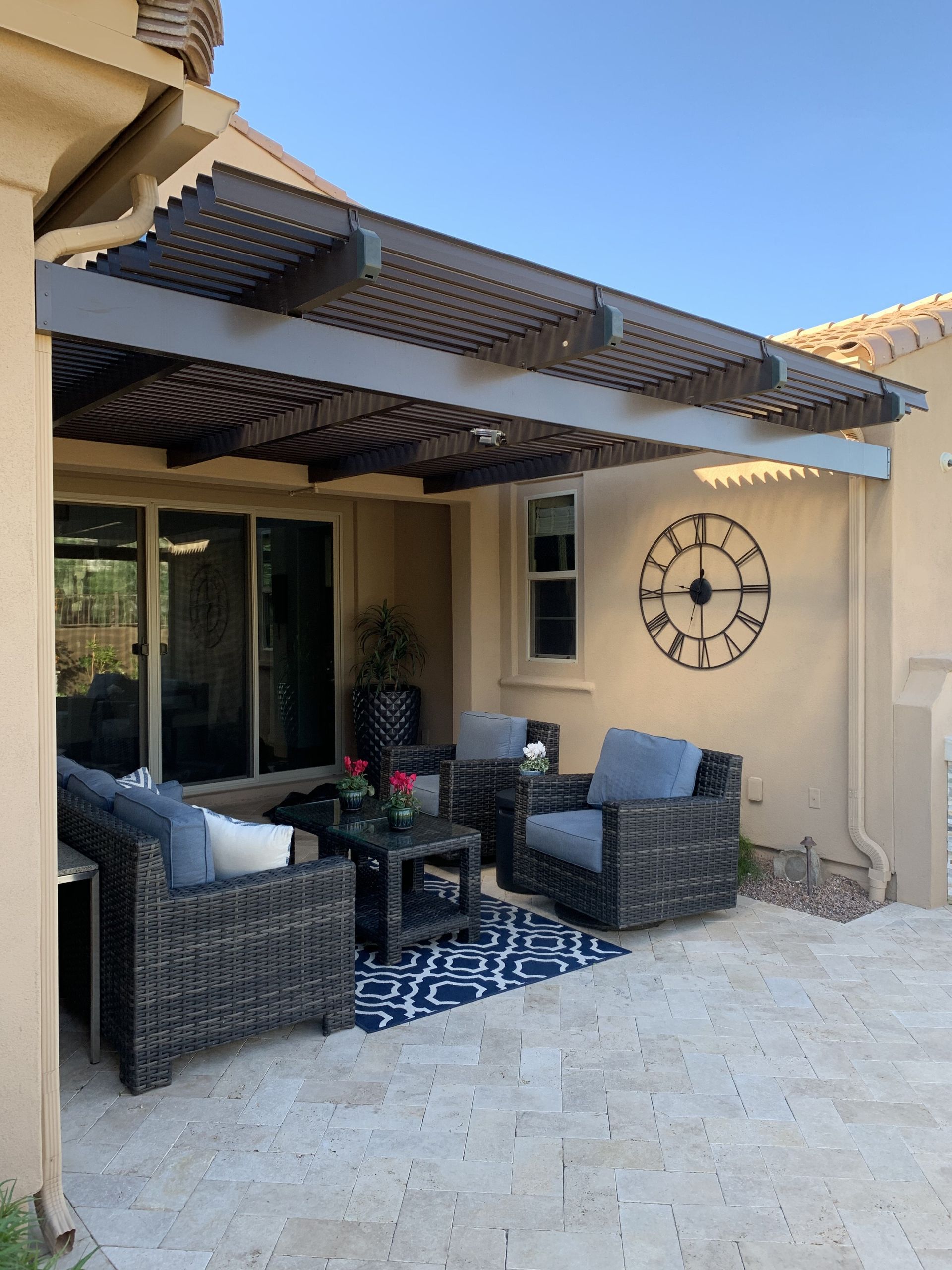 A patio with wicker furniture and a clock on the wall.