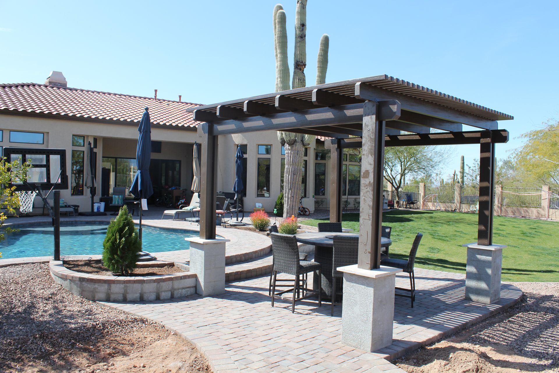 A large house with a pool and a pergola in front of it