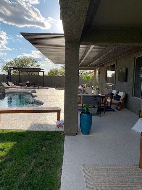 A patio with a swimming pool in the background