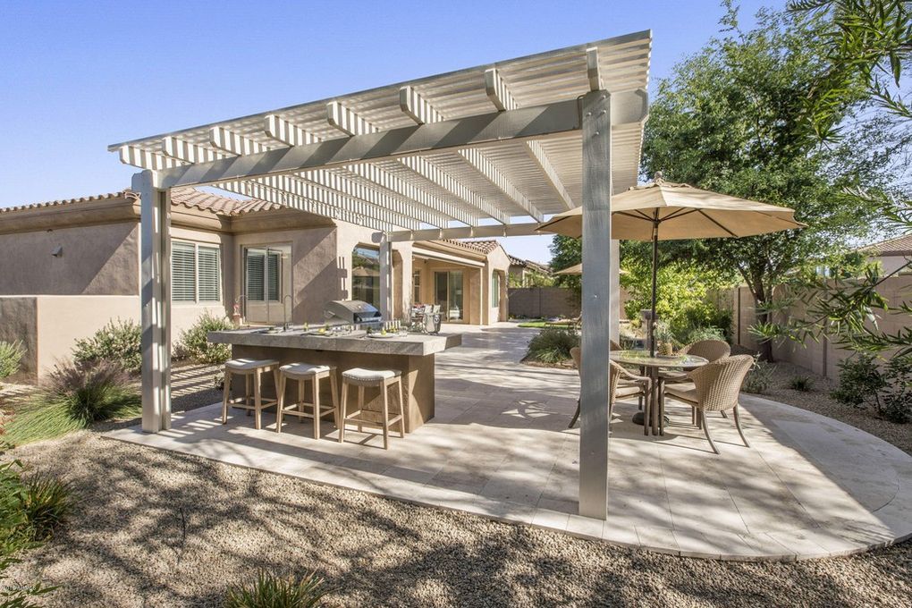 A patio with a pergola , tables , chairs and umbrellas.