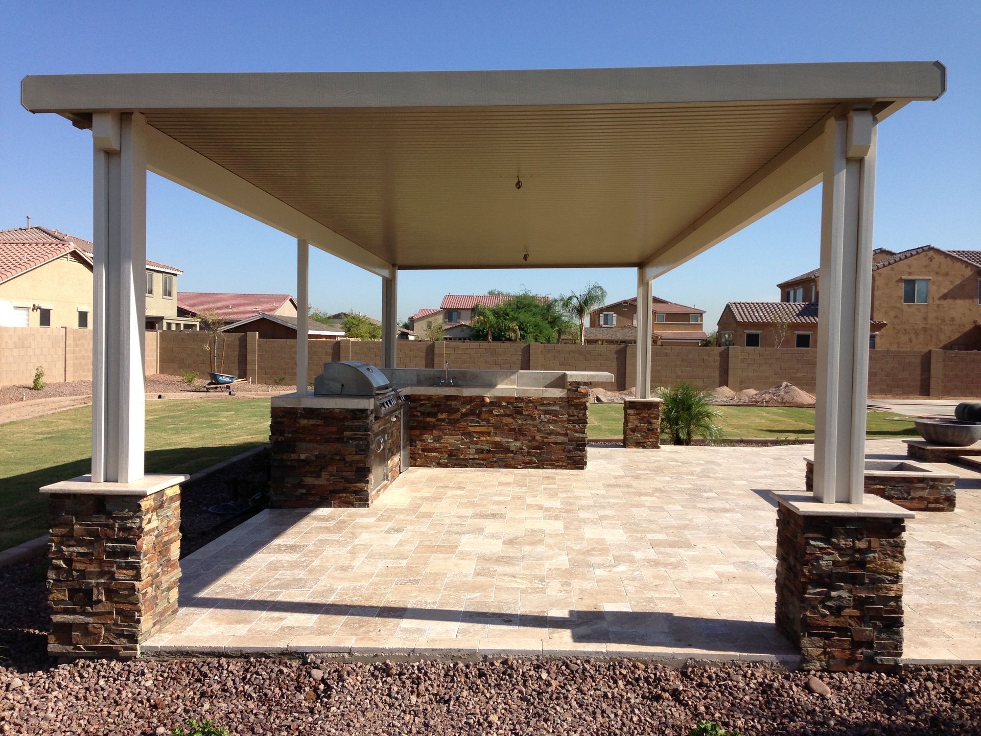 A patio with a grill under a covered area