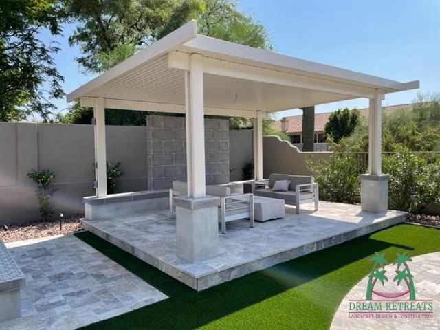 A patio with a white pergola and a few chairs
