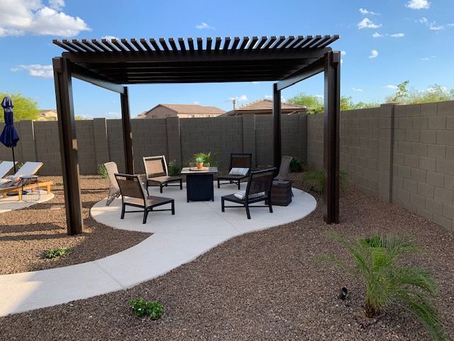 A patio with a pergola and chairs and a fire pit
