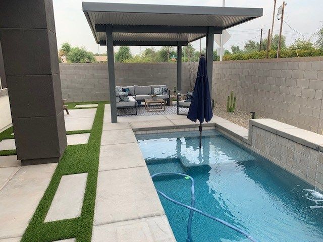 A large swimming pool with a pergola and a blue umbrella