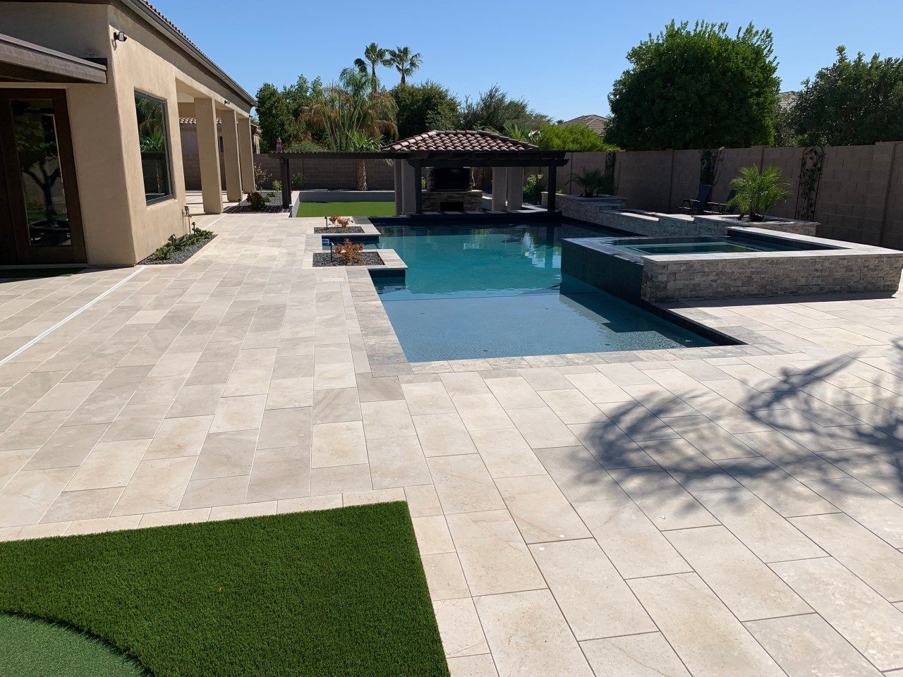 A large swimming pool is in the backyard of a house.