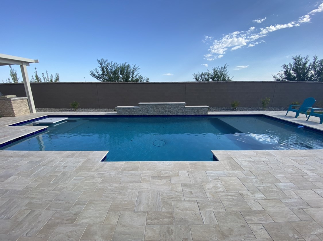A large swimming pool with a pergola and chairs around it.