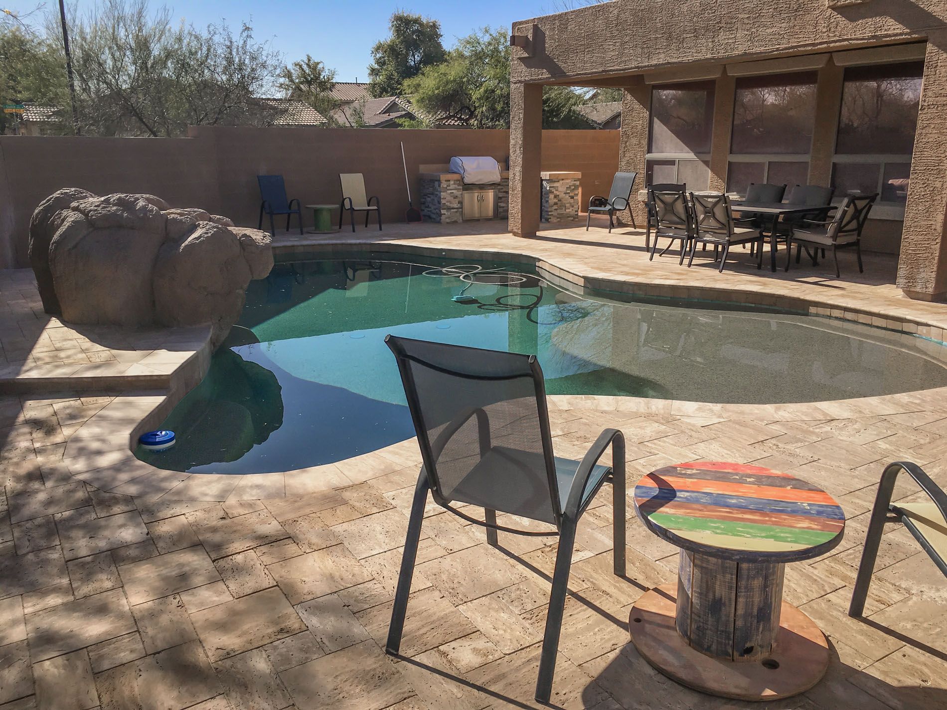 A swimming pool with chairs and a table in front of it