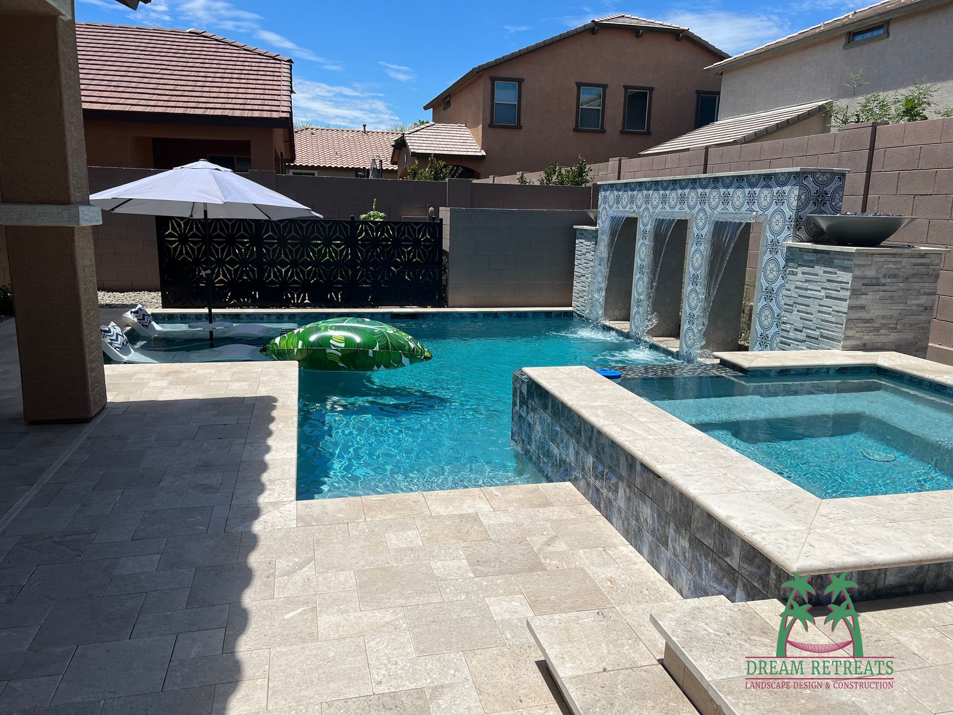 A large swimming pool with a waterfall and an umbrella