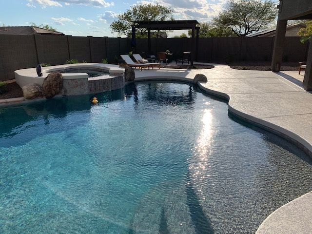 A large swimming pool with a hot tub in the backyard of a house.