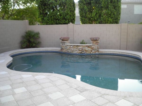 A large swimming pool surrounded by trees and a fence