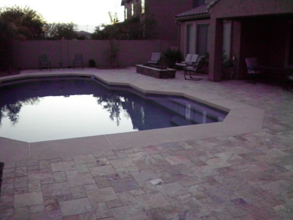A large swimming pool with a patio in front of it
