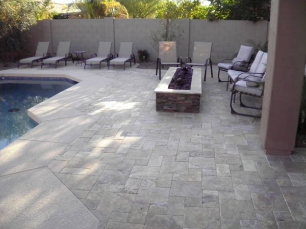 A patio with chairs and a fire pit next to a pool