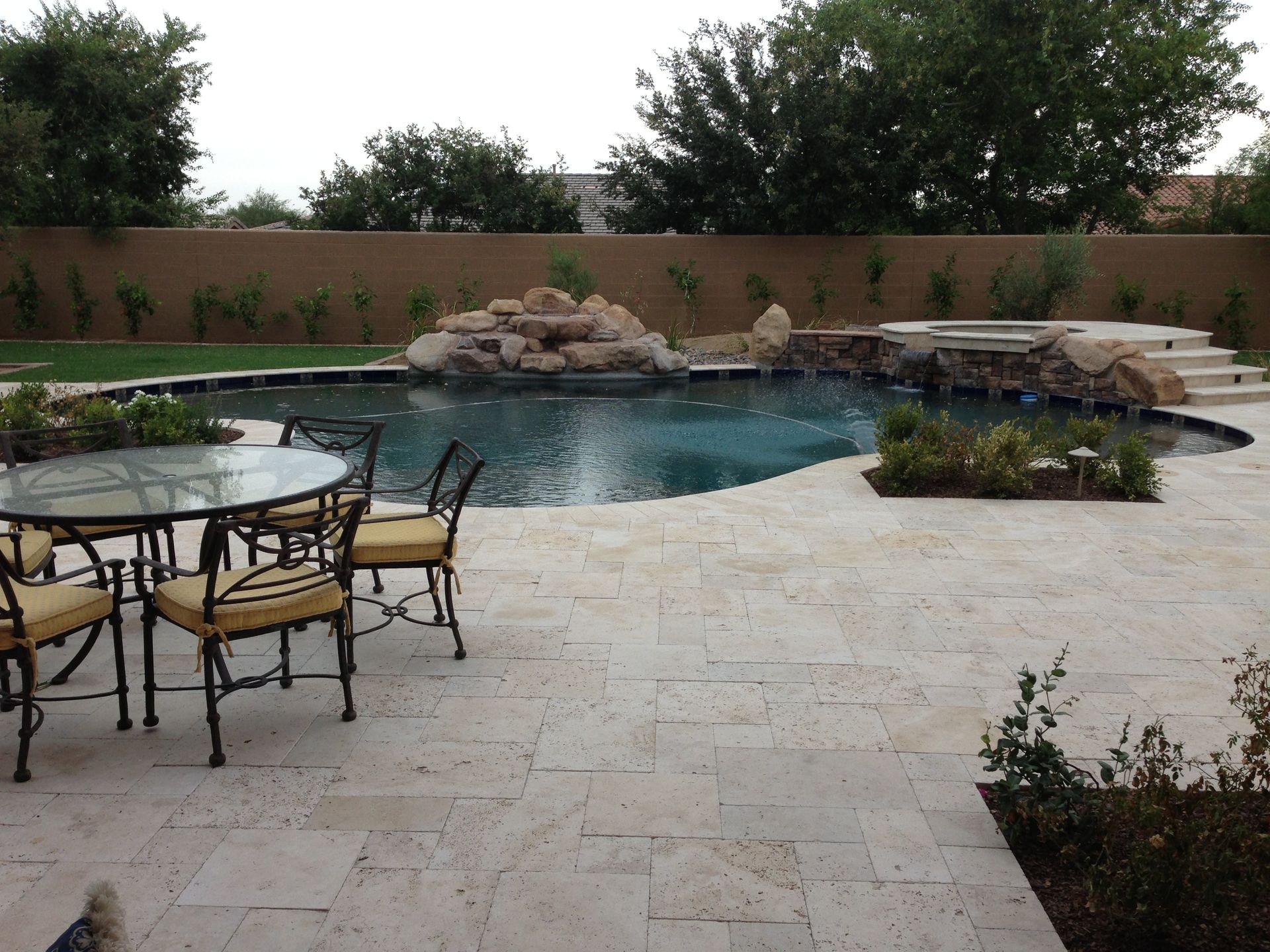 A patio with a table and chairs next to a large pool