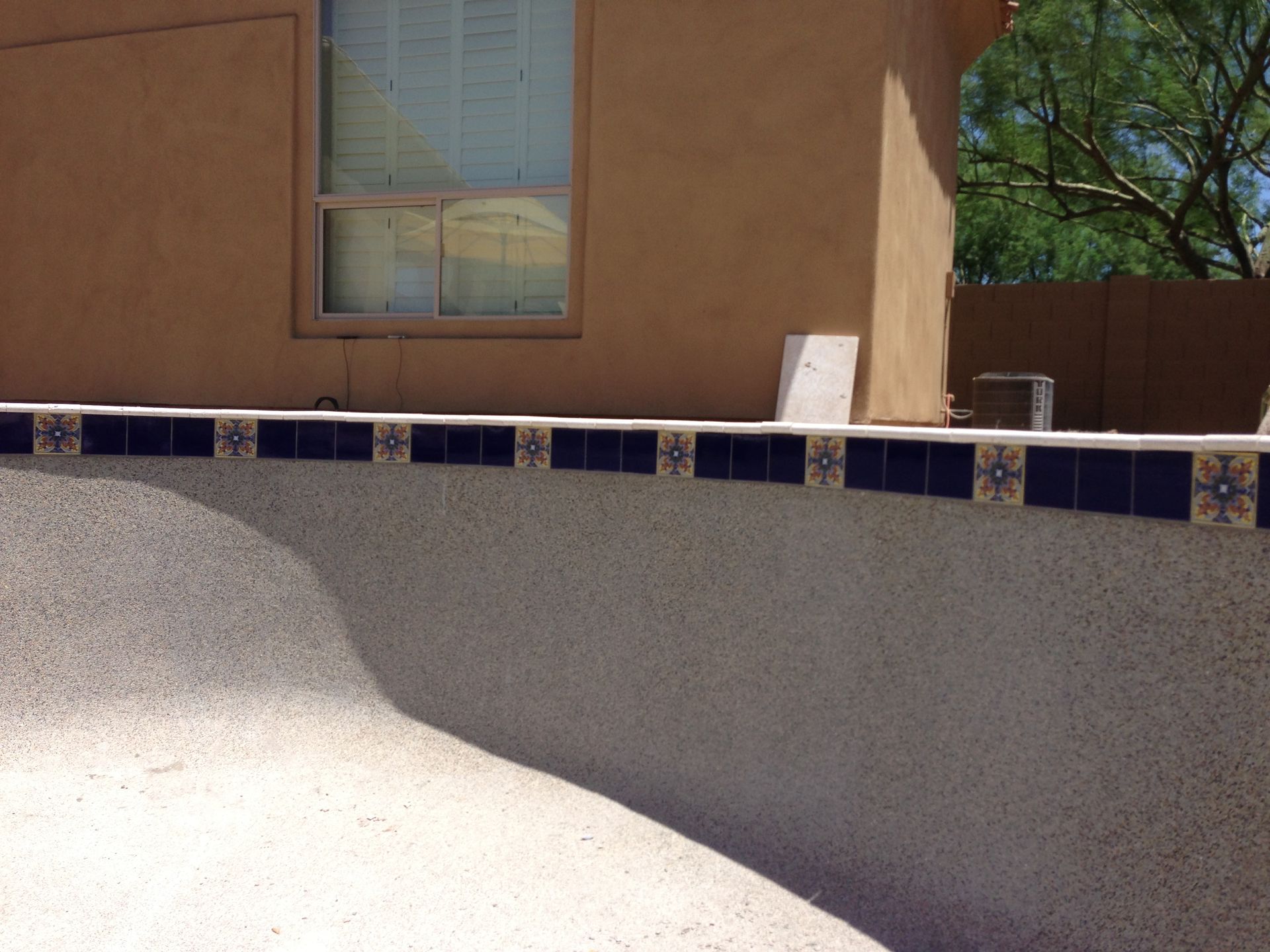 A swimming pool with blue and white tiles in front of a house
