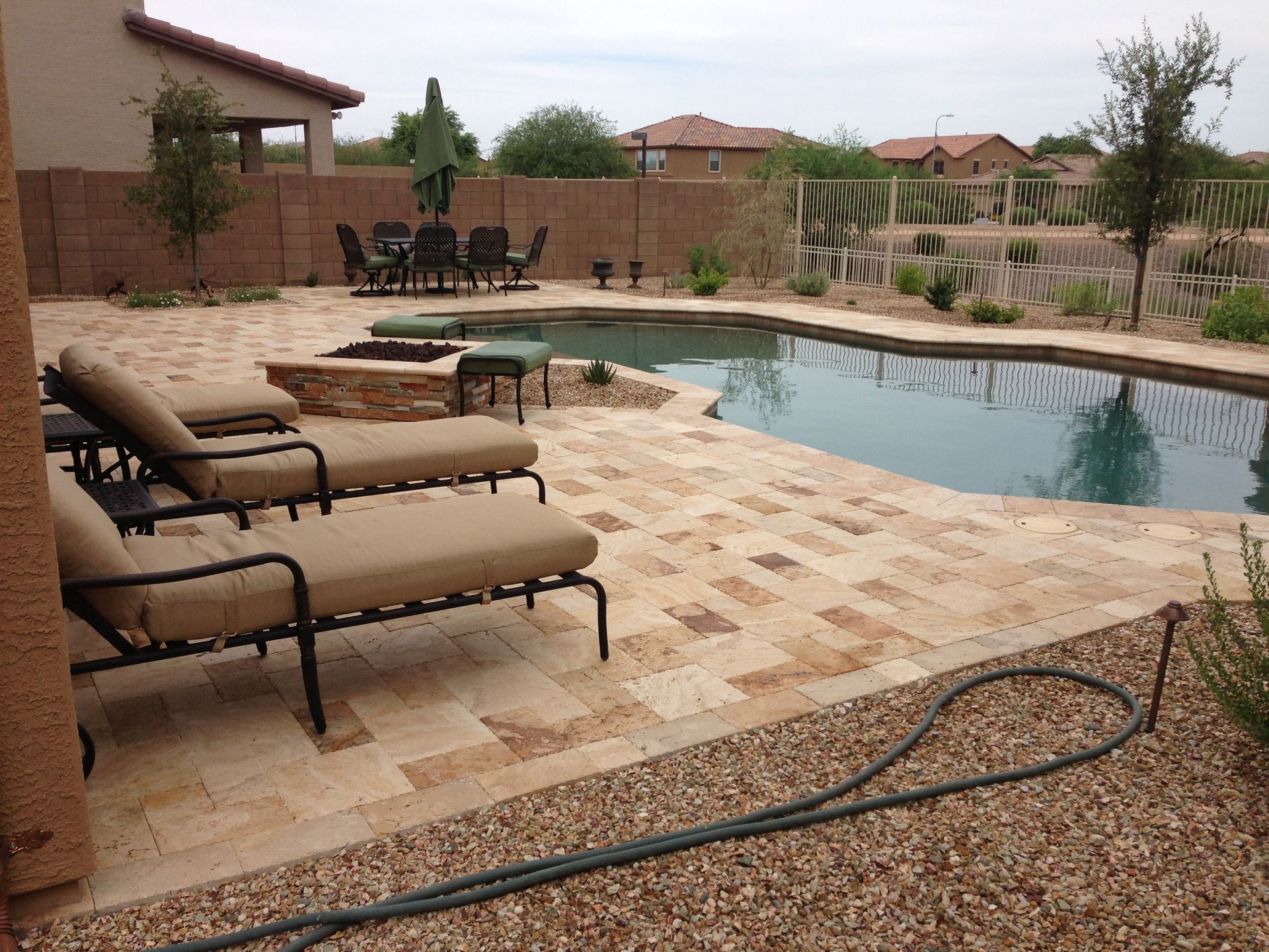 A patio with chairs and a hose next to a swimming pool