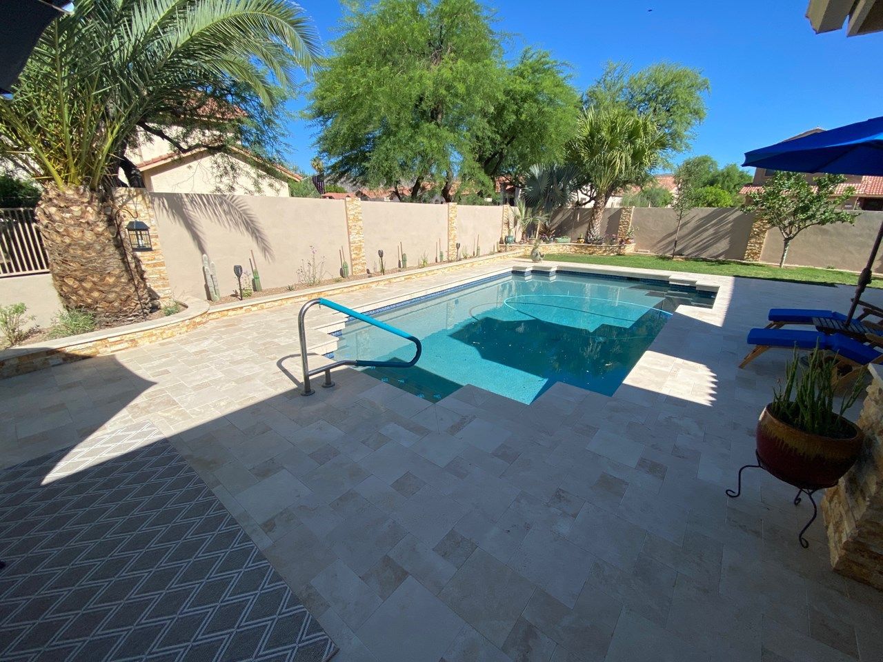 There is a large swimming pool in the backyard of a house.