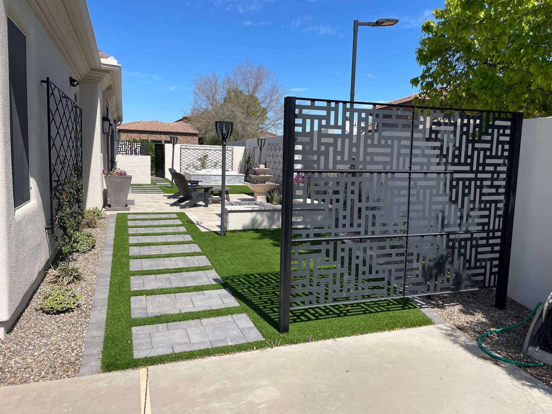 A fence with a maze pattern on it is surrounding a lush green yard.