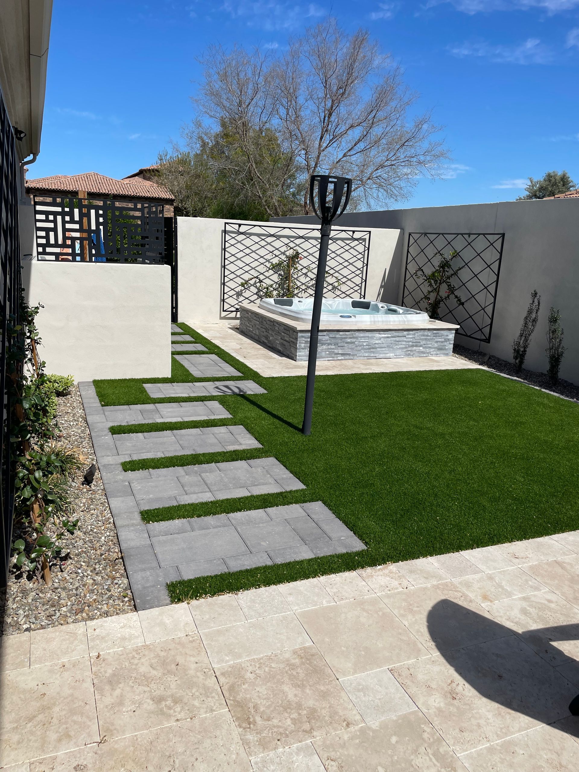 A backyard with a walkway leading to a hot tub.
