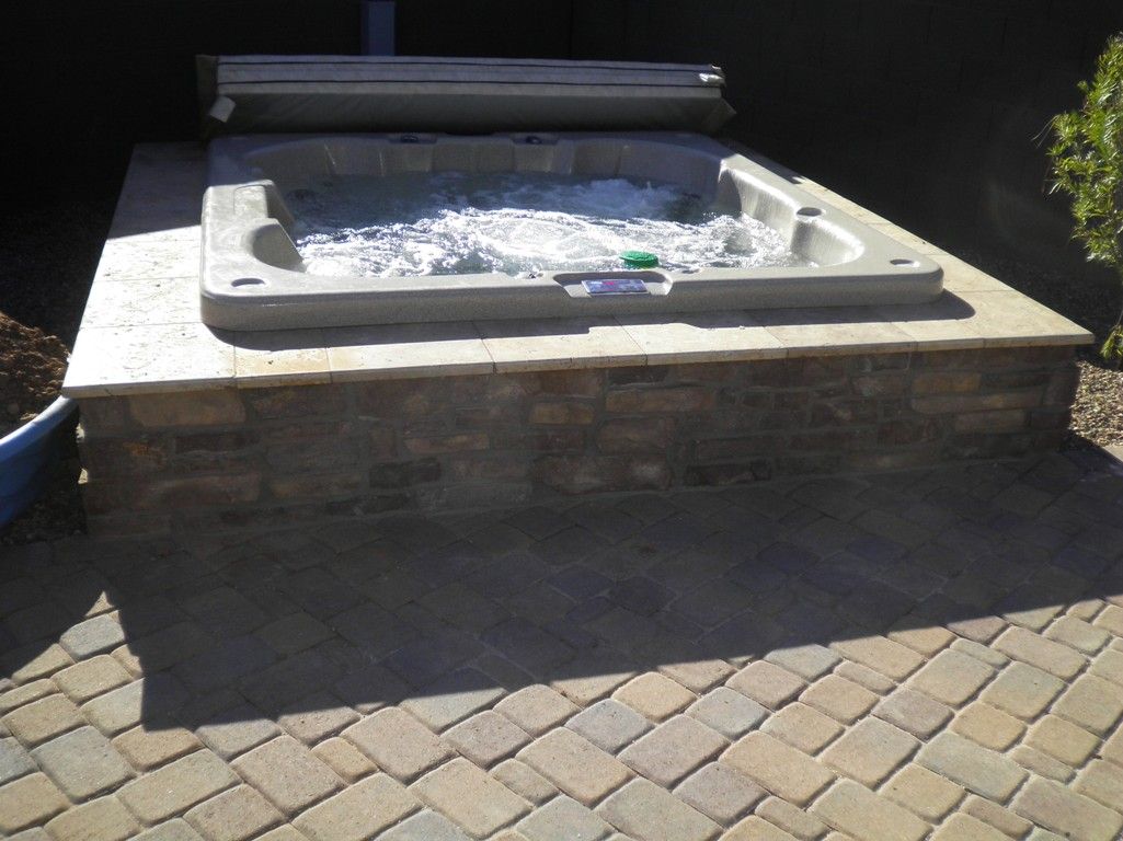 A hot tub is sitting on a brick patio
