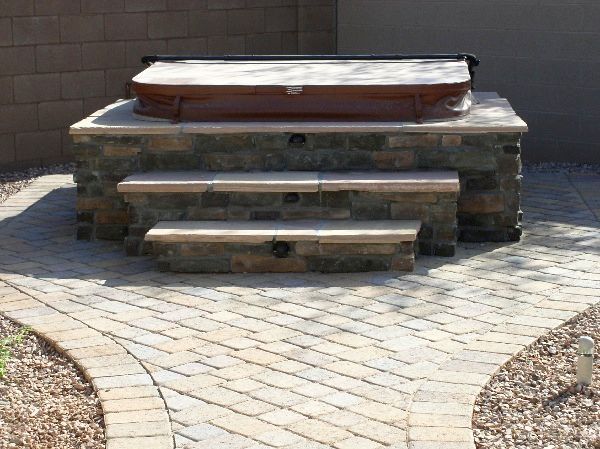 A hot tub is sitting on top of a stone patio.