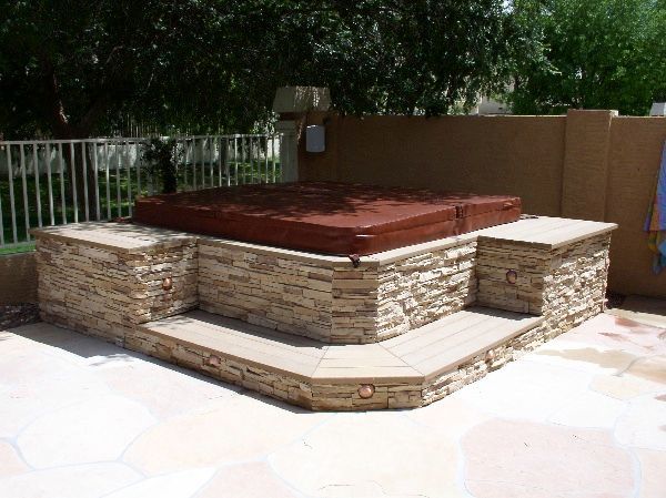 A hot tub is sitting on top of a stone patio.