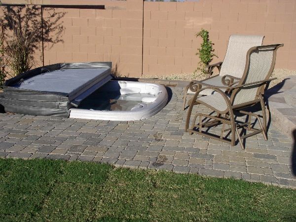 A rocking chair sits next to a hot tub on a patio